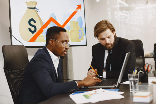 African man in a black suit. International partners. People sitting at the table with laptop.